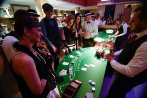 une soirée casino, avec des personnes habillées en année 30 devant la table du black jack, avec derrière un croupier qui distribue les cartes