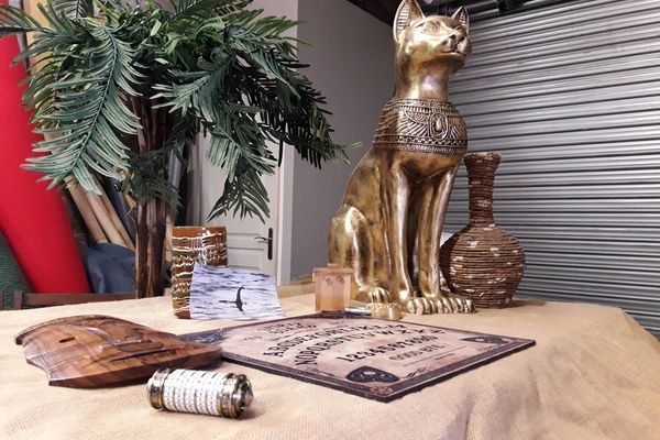 une statut de chat, un ouija des décorations d'énigmes posés sur une table