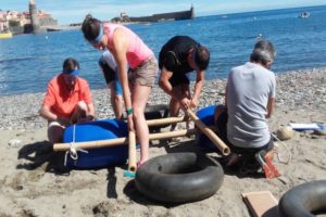 des personnes qui construisent un radeau avec du bois et bouée sur une plage