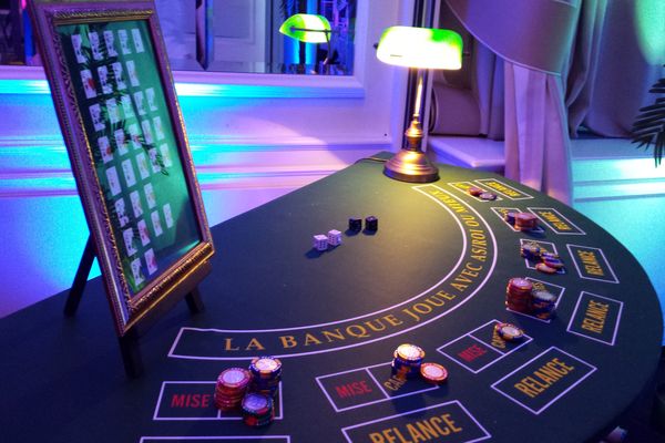 Table de casino poker prise de dessus, avec une lampe, un tableau récapitulatif des combinaisons de cartes et des jetons, sont posés dessus.