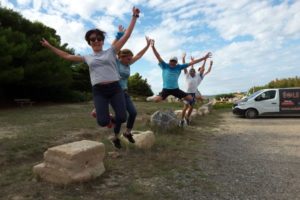 un groupe de 5 personnes qui sautent par dessus des cailloux en levant les bras en l'air