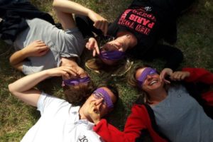 un groupe de 4 personnes qui rigolent et ont les yeux bandés par un bandana violet