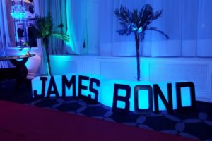 décoration james bond en grosse lettre posé contre un banc lumineux bleu.
