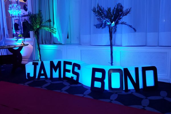 décoration james bond en grosse lettre posé contre un banc lumineux bleu.