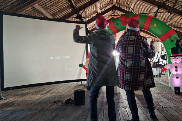 deux personnes qui chantent devant un écran géant de karaoké dans un décor de noël