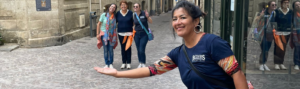une femme au premier plan qui tend son bras en souriant et un groupe de 3 femmes se tiennent plus loin debout pour faire un effet d'optique