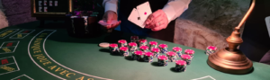 table de casino poker, avec des jetons sur la table ainsi qu'une lampe et un croupier qui montre une paire d'as