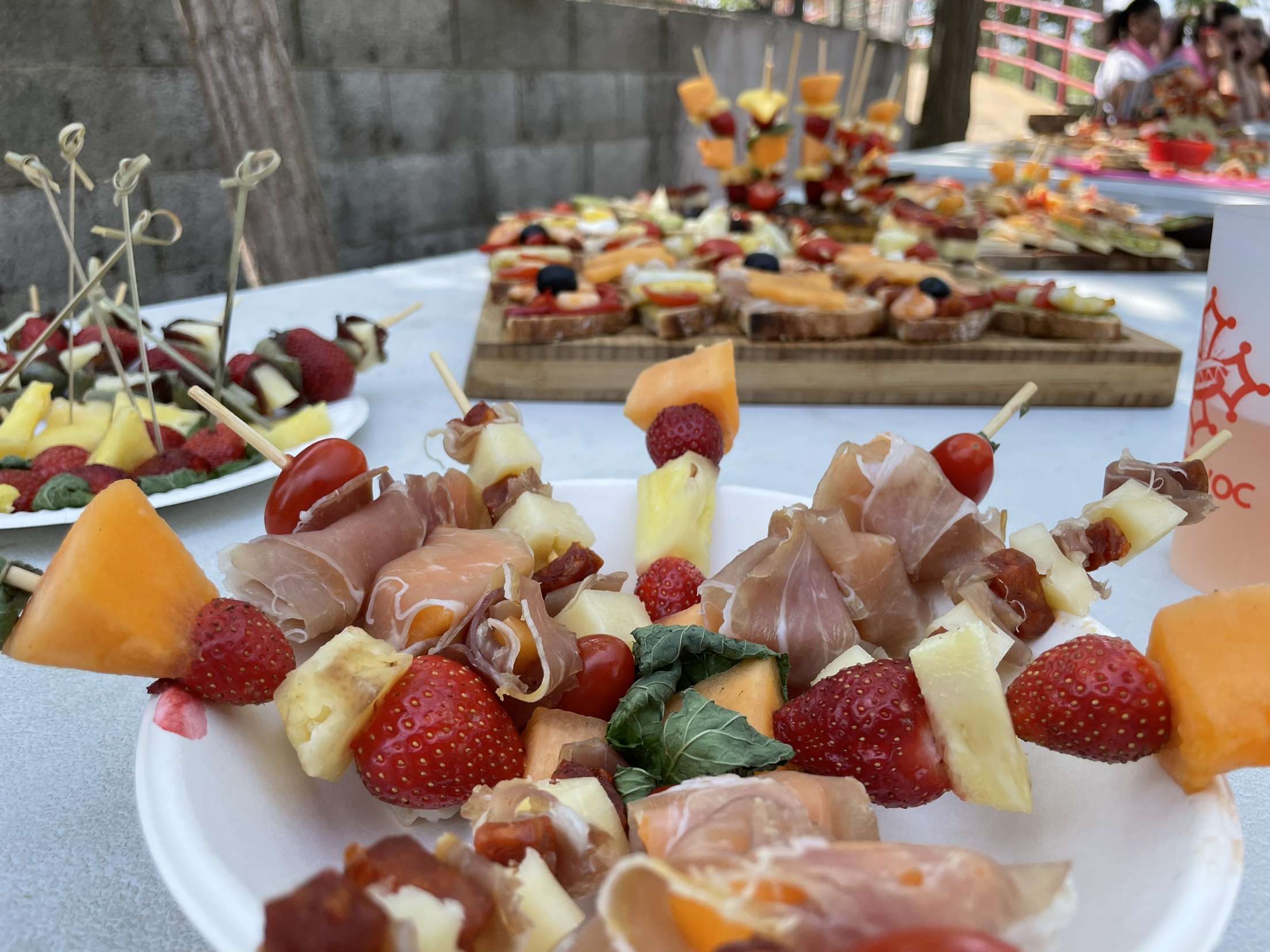 plusieurs plats de tapas avec des brochettes de charcuterie, fromage, fruits.